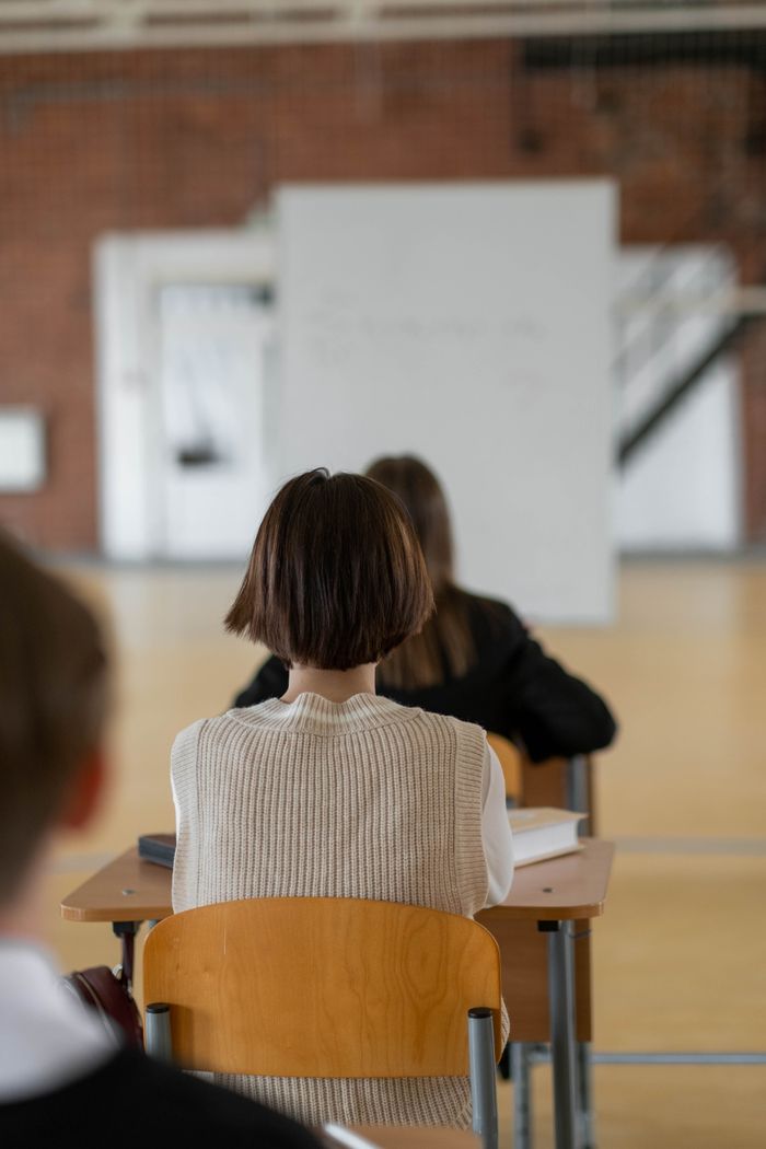 Focused students seated in class, attentively looking towards the whiteboard.